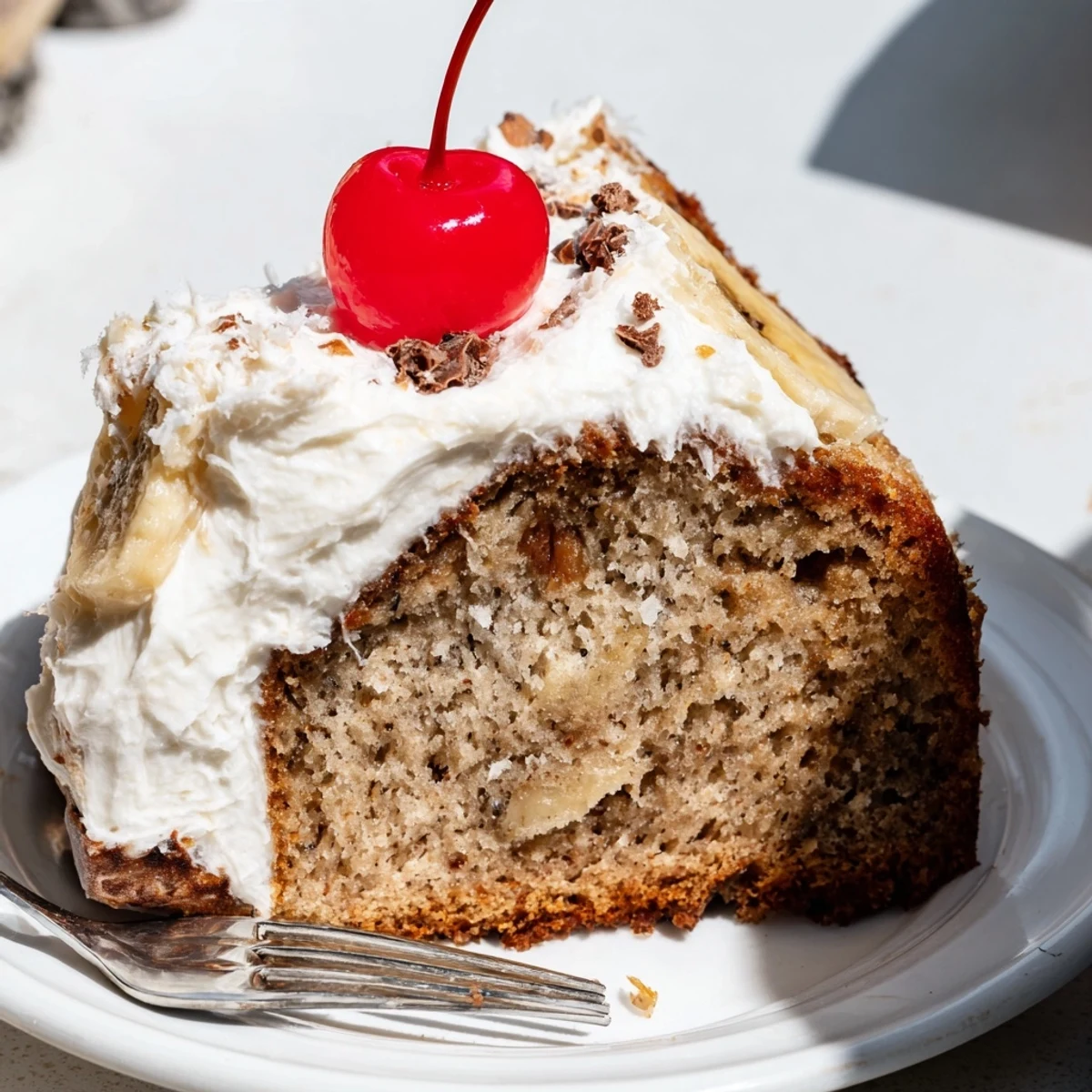Sliced Rebel Float frosted banana bread topped with creamy frosting and a cherry garnish.  