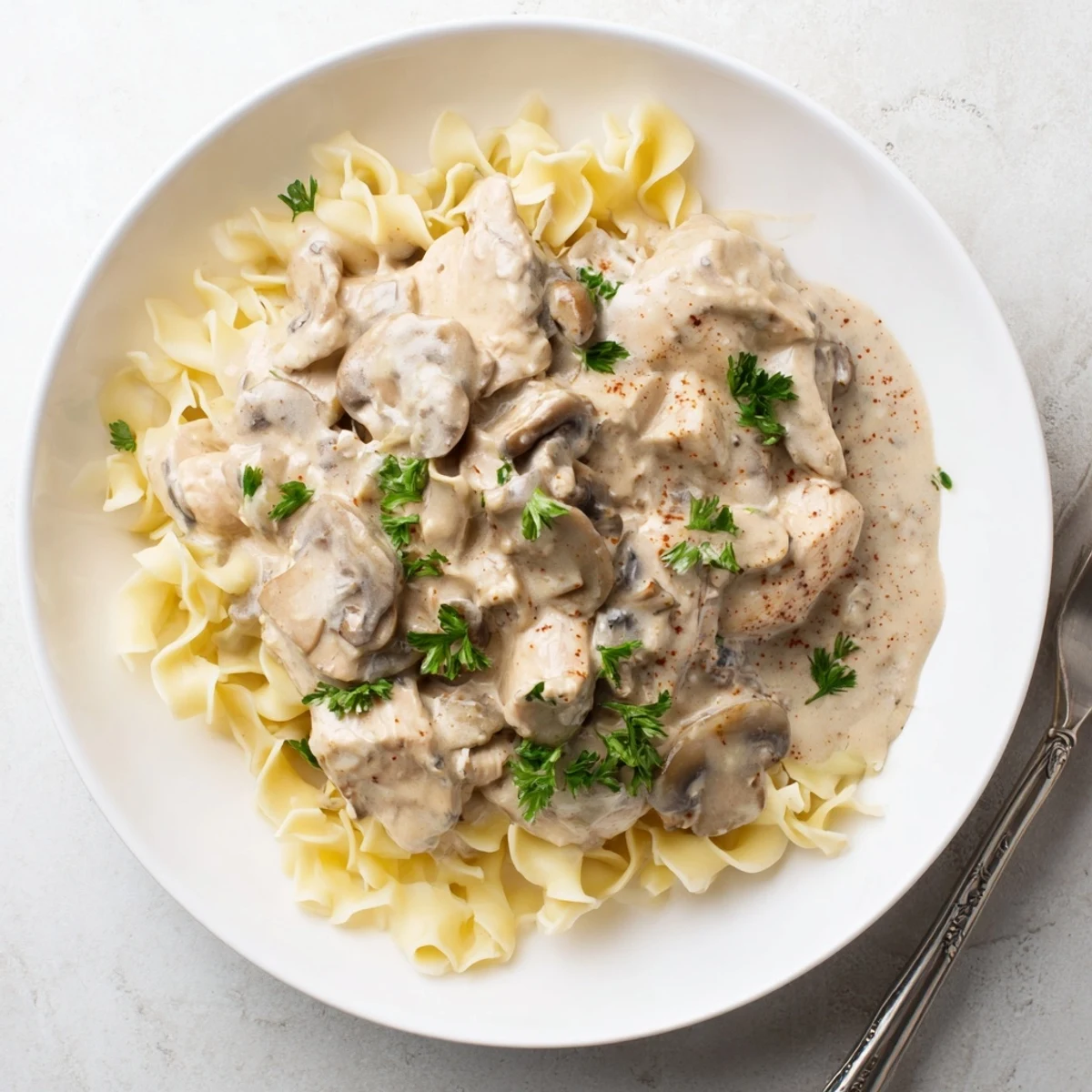 Creamy Chicken Stroganoff served over egg noodles, garnished with fresh parsley.  