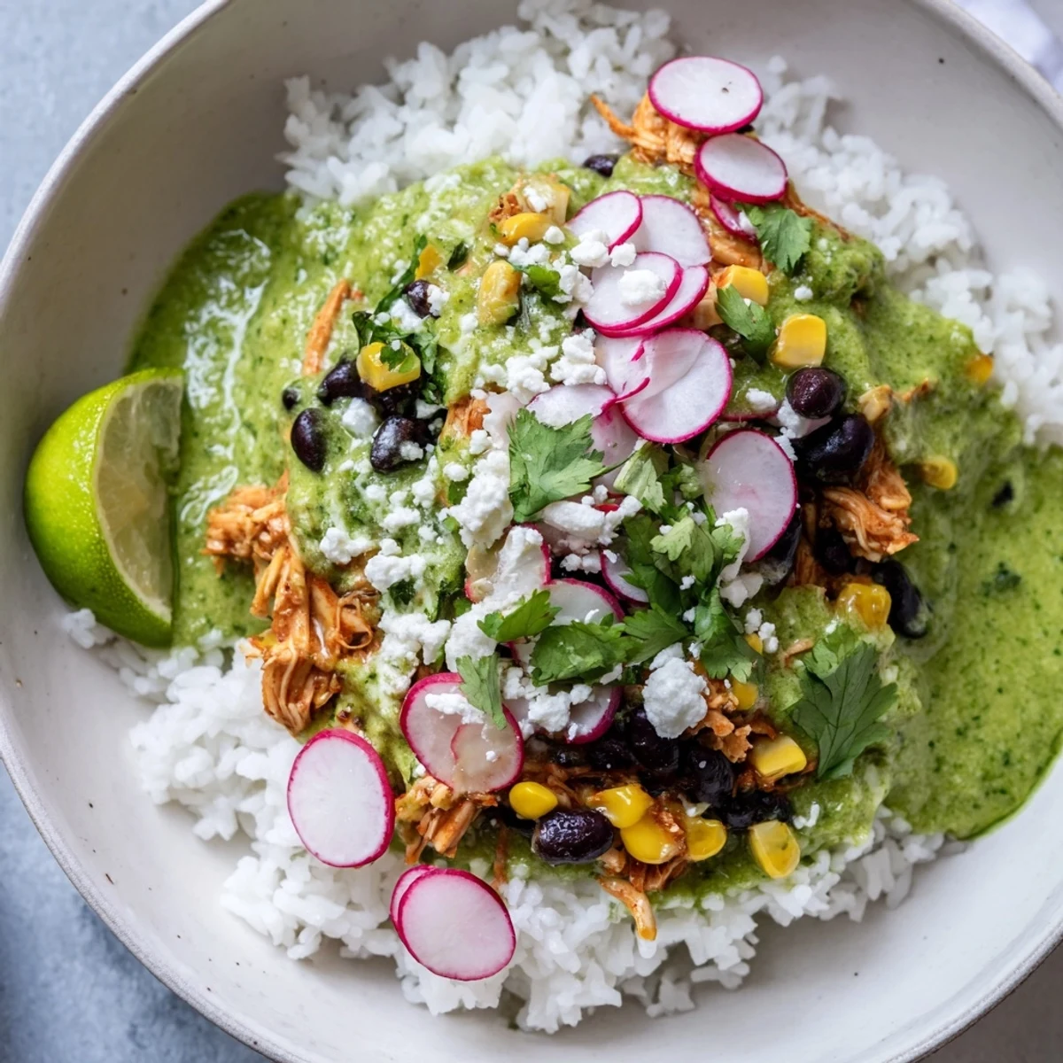 A colorful Green Enchiladas Rice Bowl overflowing with chicken, fresh cilantro, and creamy avocado slices.