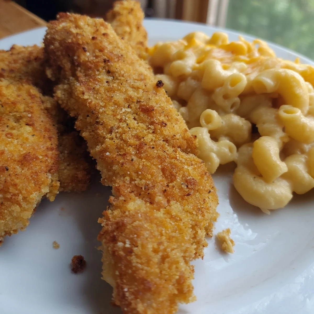 Golden, crispy chicken tenders alongside creamy mac and cheese, a classic American comfort food meal.