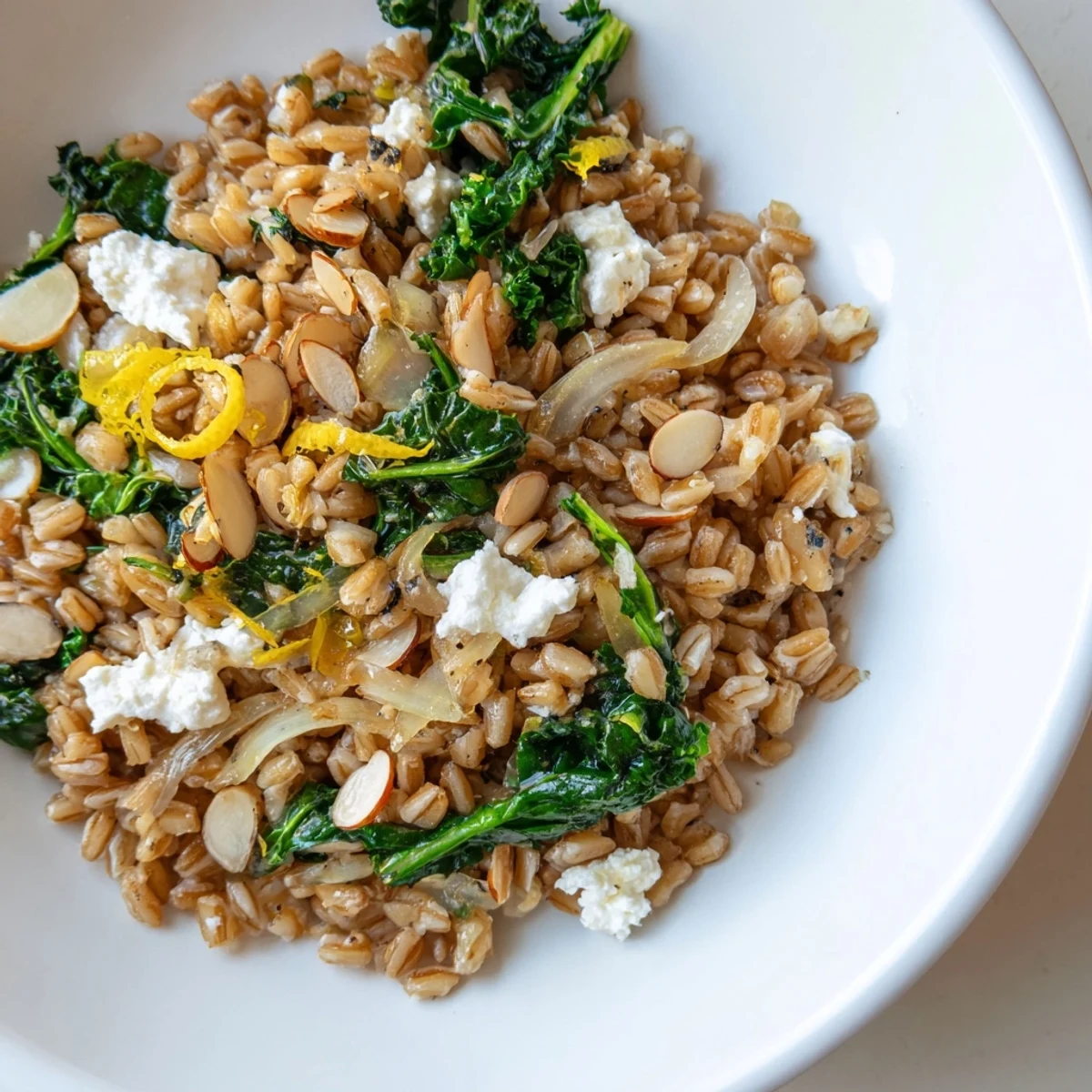 Steaming warm farro and greens pilaf, topped with golden toasted almonds, ready to serve.