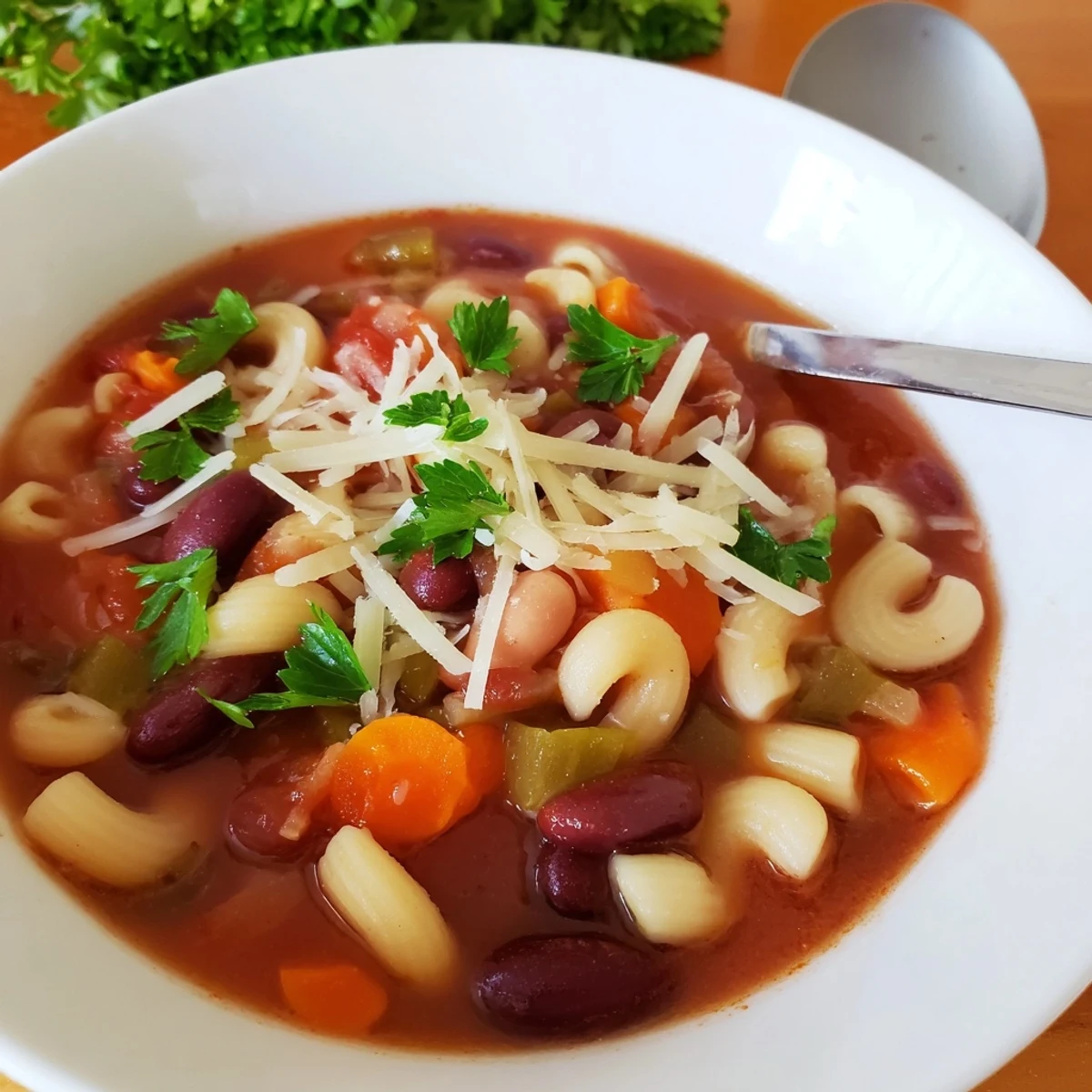Steaming bowl of Pasta e Fagioli Soup, garnished with fresh parsley and Parmesan cheese, ready to enjoy.