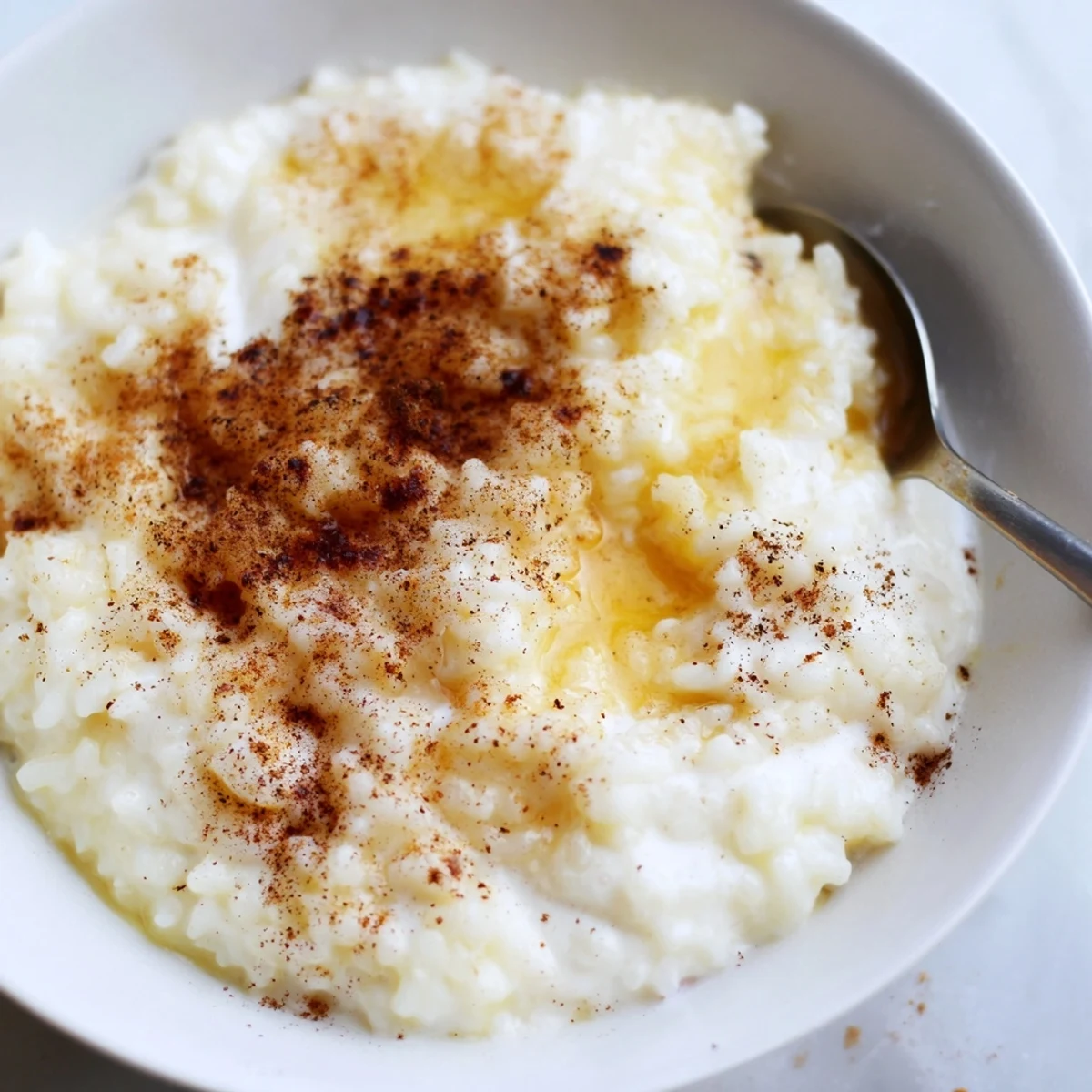 A warm bowl of creamy Rice Pudding with Leftover Rice, finished with a generous dusting of cinnamon.