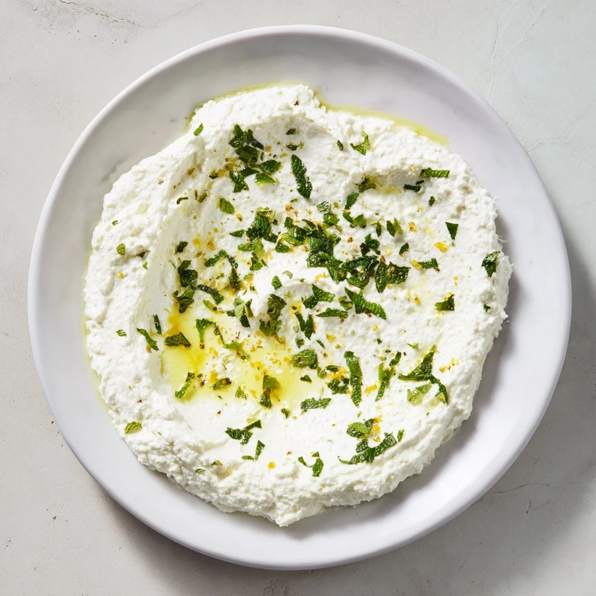 Whipped feta dip with vibrant lemon-mint drizzle, perfect appetizer served with pita bread.