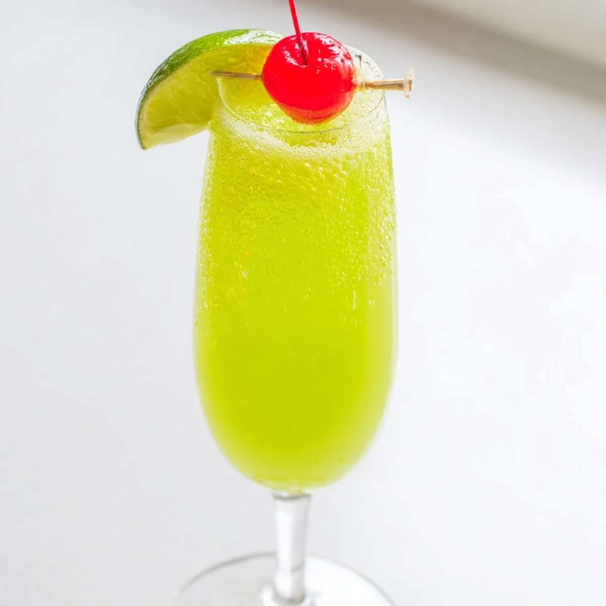 Festive Quick Grinch Mimosa Mocktails in flutes, green and bubbly, ready for a Christmas celebration.