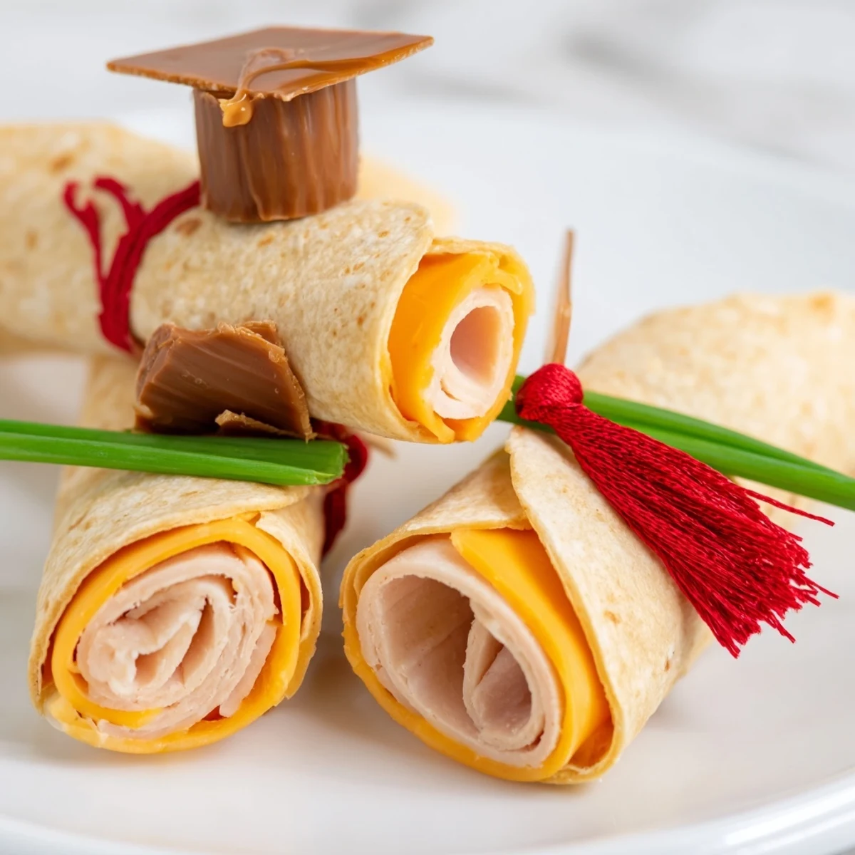 These festive Graduation Cap Diploma Snack Wraps combine rolled tortillas with cap and tassel crackers creatively.