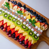 Delicious fruit art: This Happy Birthday Cake Slice Fruit Board sparkles with vibrant berries and pineapple.