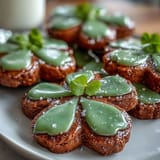 Delicate buttery sugar cookies cut into shamrock shapes and decorated with glossy green royal icing for a cheerful holiday treat.