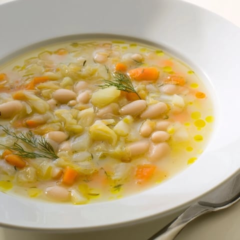 Creamy white bean and fennel soup, garnished with fennel fronds, ready to serve as a warm, delicious meal.