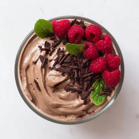 Decadent avocado chocolate mousse, featuring fresh raspberries and a dusting of chocolate shavings.