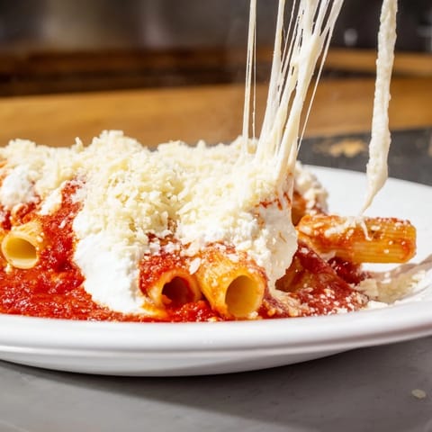 A close-up of cheesy, bubbling slow cooker baked ziti, a satisfying Italian-American comfort food meal.