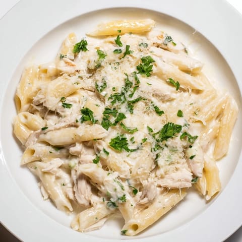 Tender shredded chicken and penne pasta smothered in a rich cream sauce, part of Tinis Creamy Chicken Pasta.