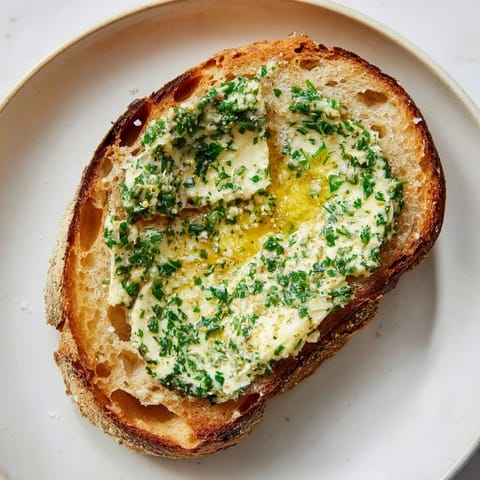 Melted herb butter gently soaking into toasted bread; a simple yet delicious herb butter toast recipe.