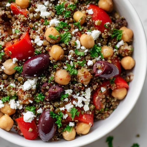 This Greek Power Salad features vibrant red cherry tomatoes, diced cucumber, and fresh parsley, tossed in a zesty Greek vinaigrette for a bright, tangy flavor.