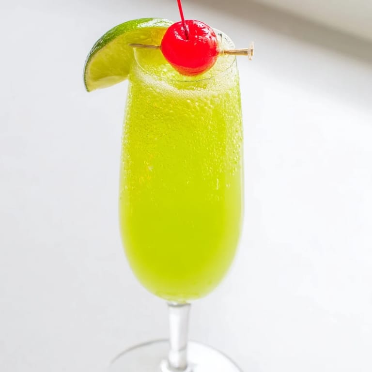 Festive Quick Grinch Mimosa Mocktails in flutes, green and bubbly, ready for a Christmas celebration.
