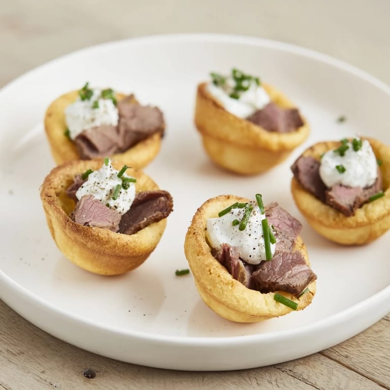 Imagine a close-up of Express Holiday Yorkshire Pudding Bites: pillowy, roast beef-filled appetizers with chive garnish.