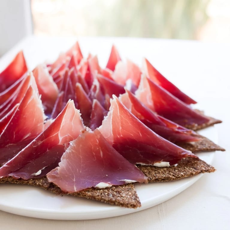 Elegant presentation of The Paper Crane, an appetizer with folded meats, carrot accents, and sesame seeds.