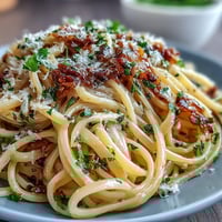 Vibrant lemon butter pasta with peas and Parmesan, served in a white bowl with a sprinkle of fresh parsley and lemon zest.